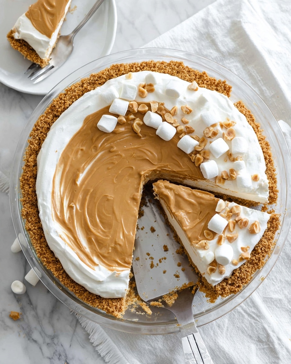 The image shows a pie with three distinct layers in a clear dish placed on a white marbled texture. The bottom layer is a crumbly golden crust that forms the pie base and edges. The middle layer is a thick, smooth white cream filling spread evenly above the crust. The top layer is a rich, light brown peanut butter topping that covers the cream almost completely, with a few swirls visible. On one side of the pie, there is a slice removed, revealing the layers clearly, and the slice rests beside the pie on the white marbled texture. A metal pie server with a white handle is under the slice. Small white marshmallows and chopped peanuts are scattered on part of the peanut butter layer and some have fallen on the marbled surface. In the upper left corner, there is a white plate with a partial piece of the pie and a fork. photo taken with an iphone --ar 4:5 --v 7